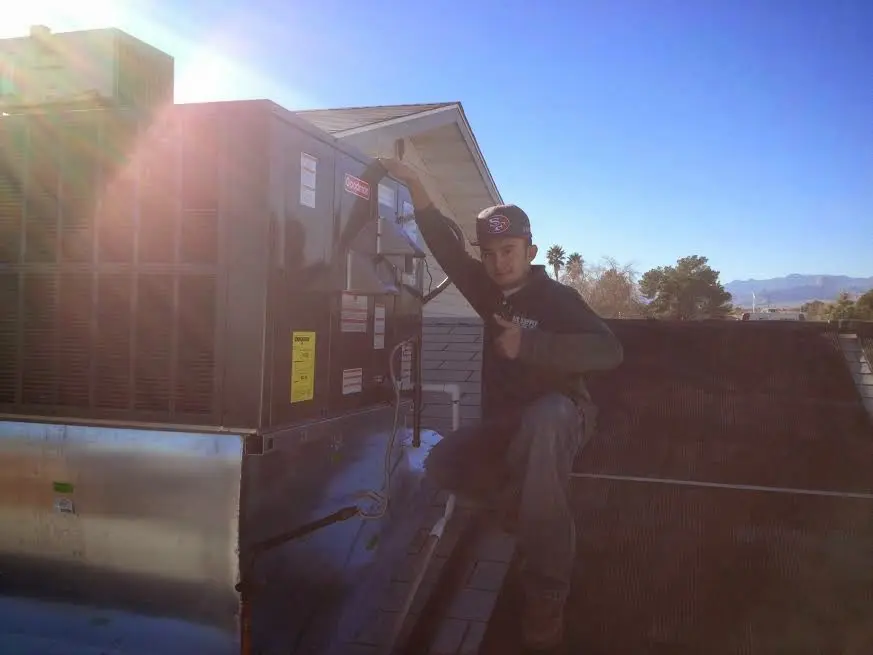 HVAC technician performing Air Duct Cleaning on a rooftop unit in Wilton